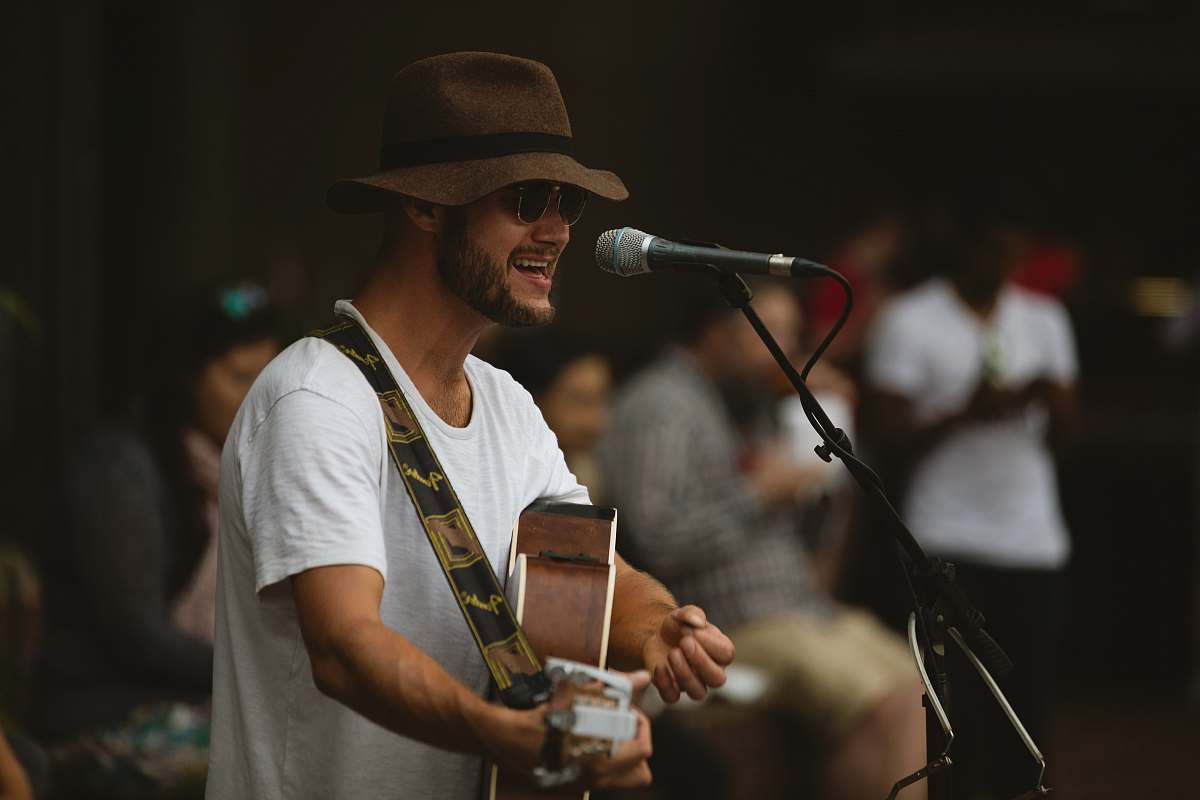 person selective focus photography of man playing guitar and using microphone human