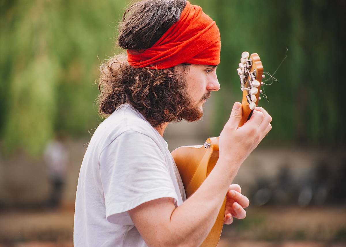 human shallow focus photography of man playing guitar outdoors playing