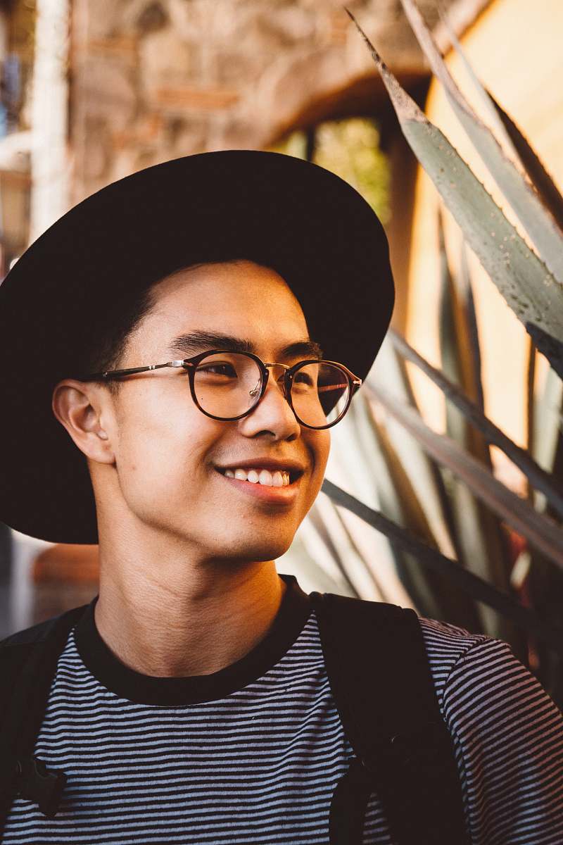 human smiling man wearing black framed eyeglasses and hat person