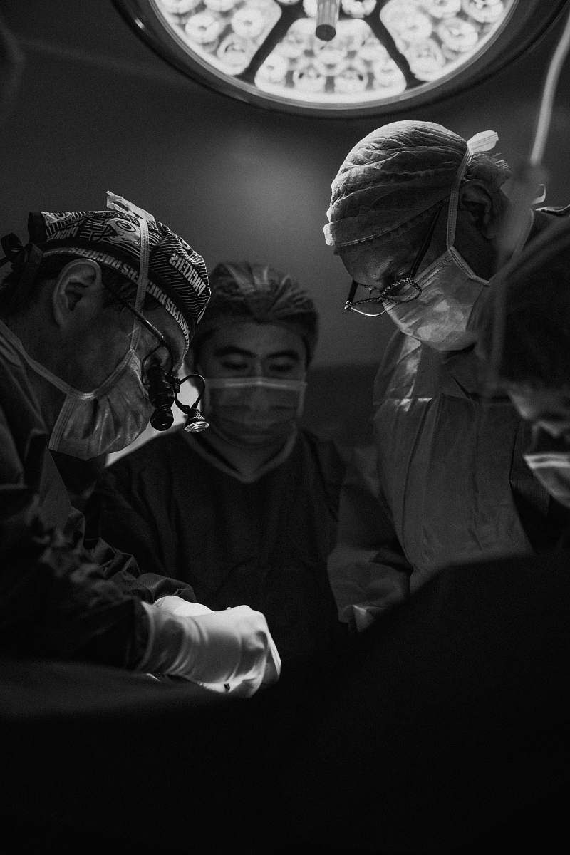 human gray scale photo of three nurses and doctor about to perform surgery black-and-white