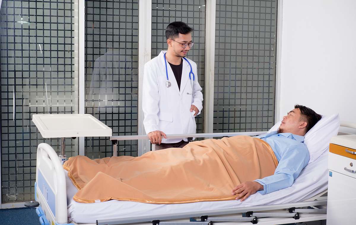 human man lying on bed talking to doctor people