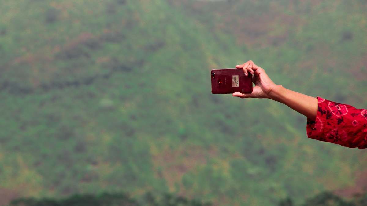 human person holding maroon smartphone photo