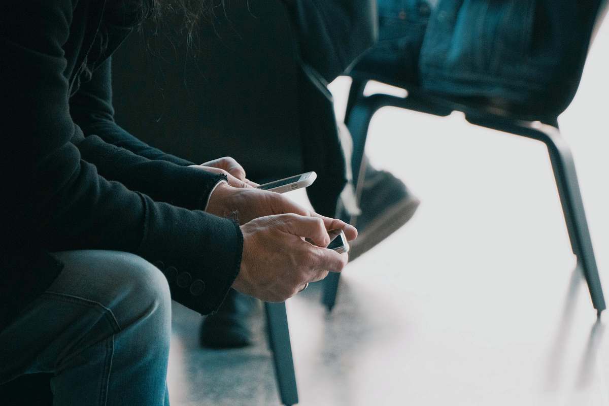 human person sitting on chair while using smartphone close-up photo people
