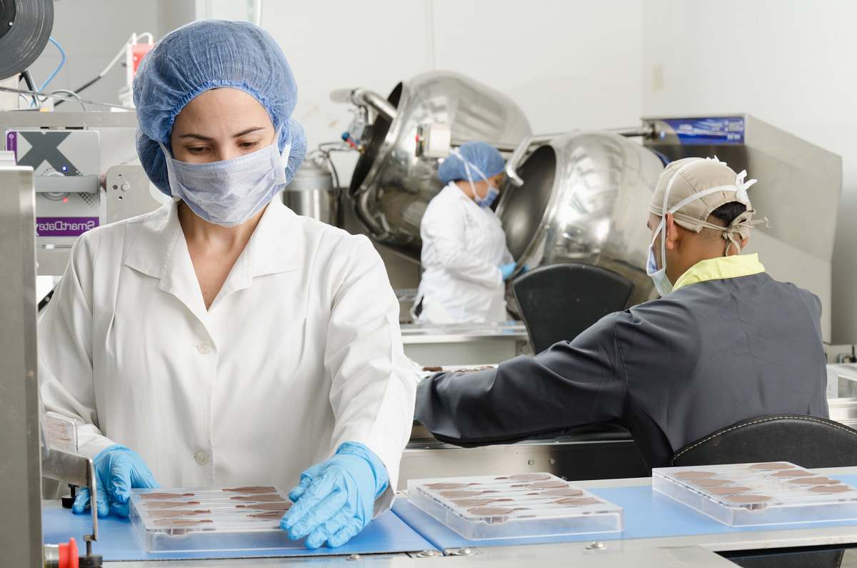 human three people inside factory wearing masks and coats clinic