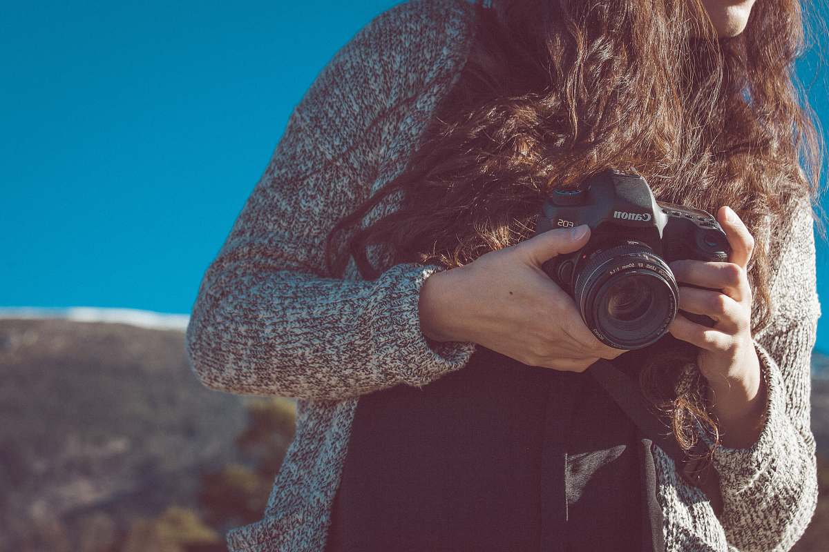 human woman holding black Canon DSLR camera canon