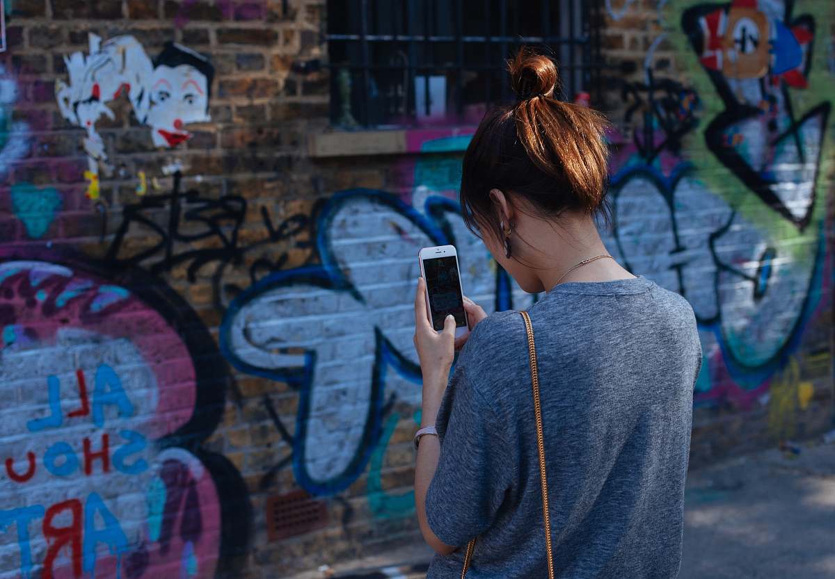 people woman looking at smartphone graffiti