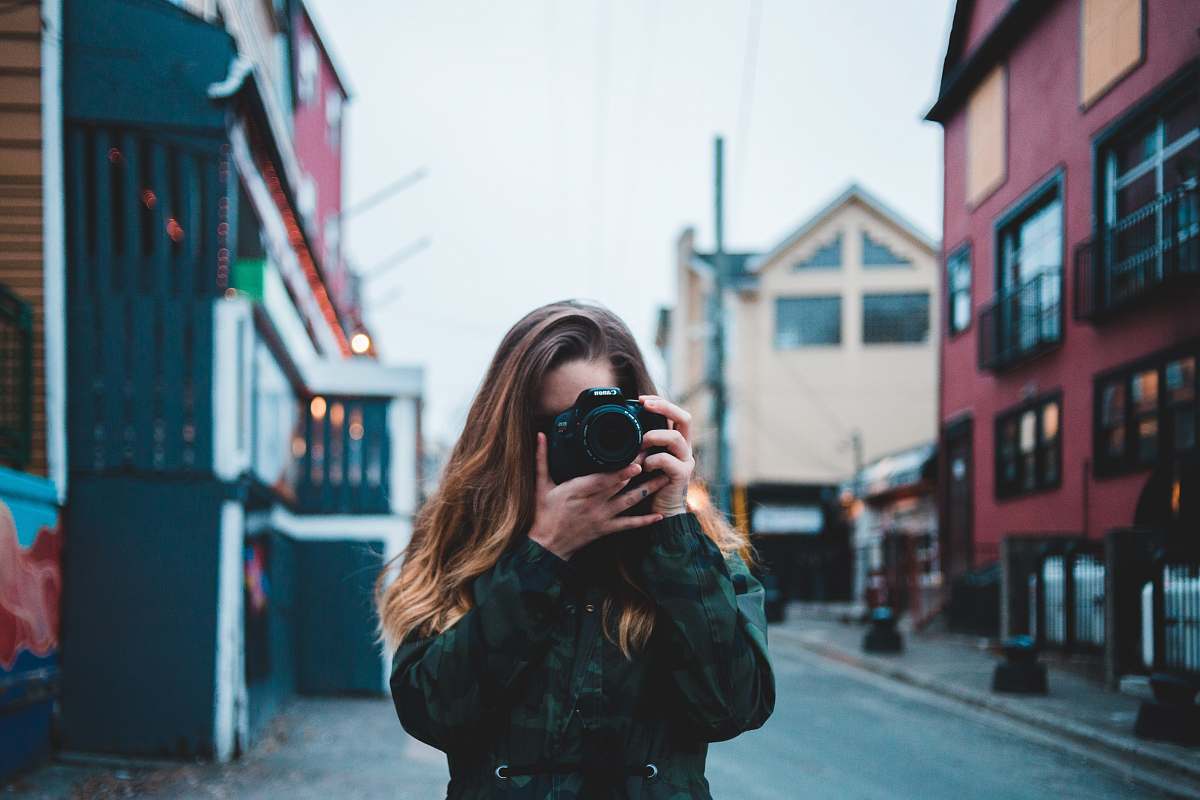 This stunning image captures a talented woman focused on using her DSLR camera to photograph a bustling street scene. With her keen eye for detail, she encapsulates the vibrancy of urban life, making this shot perfect for blogs, marketing campaigns, or photography portfolios. Whether you're showcasing city culture, street art, or everyday life, this image is an ideal fit for a range of creative projects.