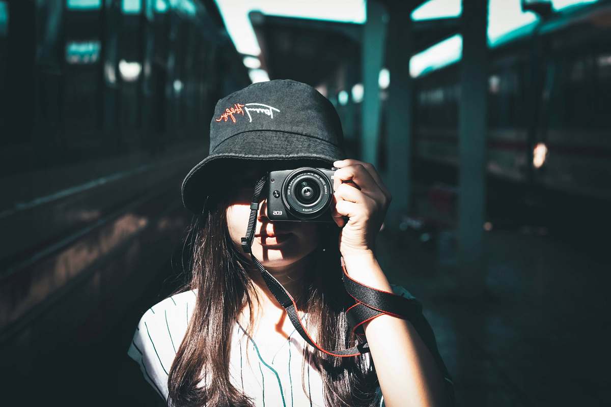 human woman wearing black bucket hat holding camera photo