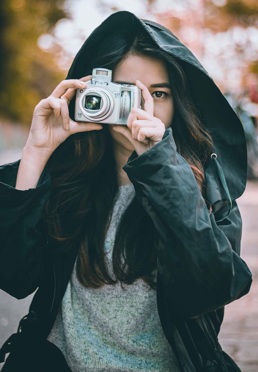 camera woman wearing jacket holding camera electronics