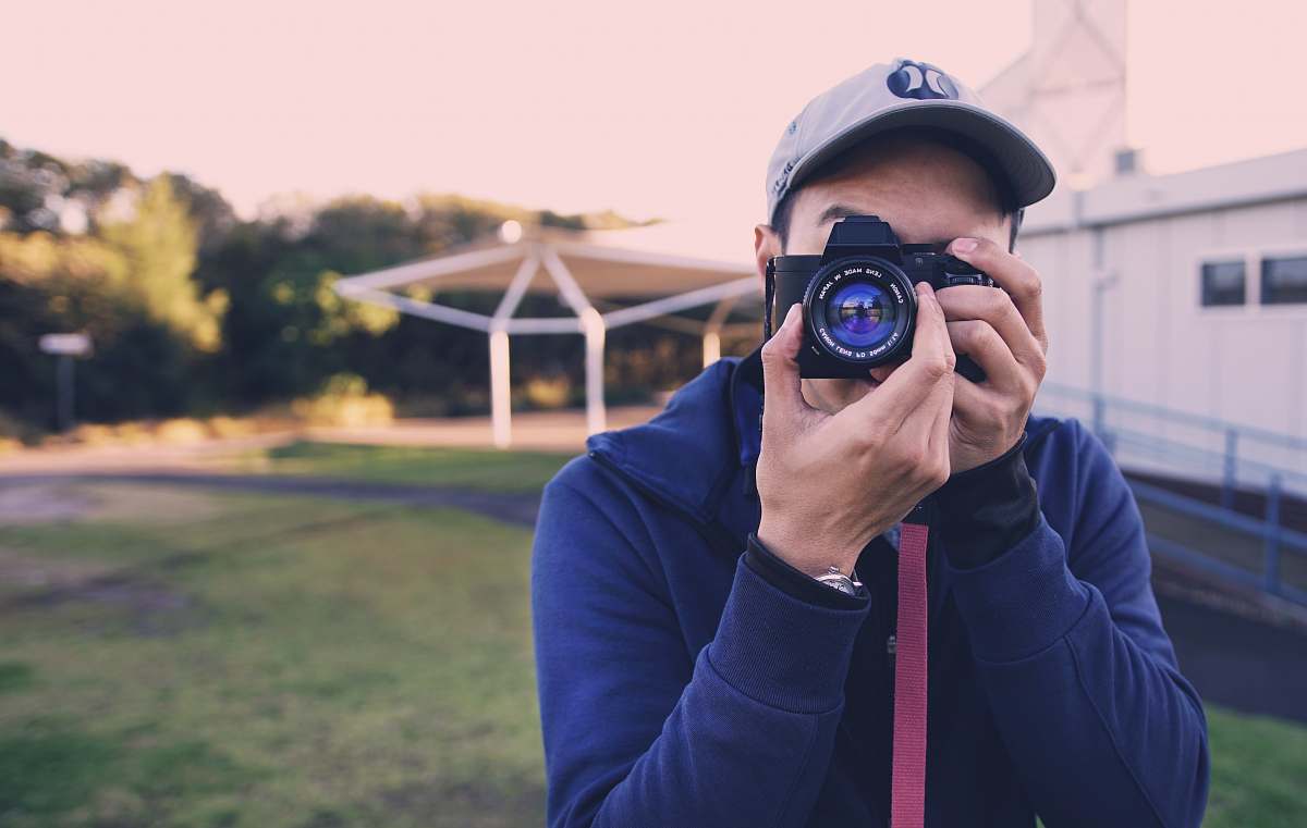 A focused man is seen using a camera to capture the stunning details of a building, showcasing the art of photography in urban environments. This image beautifully illustrates the intersection of human creativity and architectural design, making it perfect for articles on photography, urban exploration, or architectural showcases. Ideal for use in blogs, marketing materials, or social media posts that highlight the importance of documenting our surroundings.