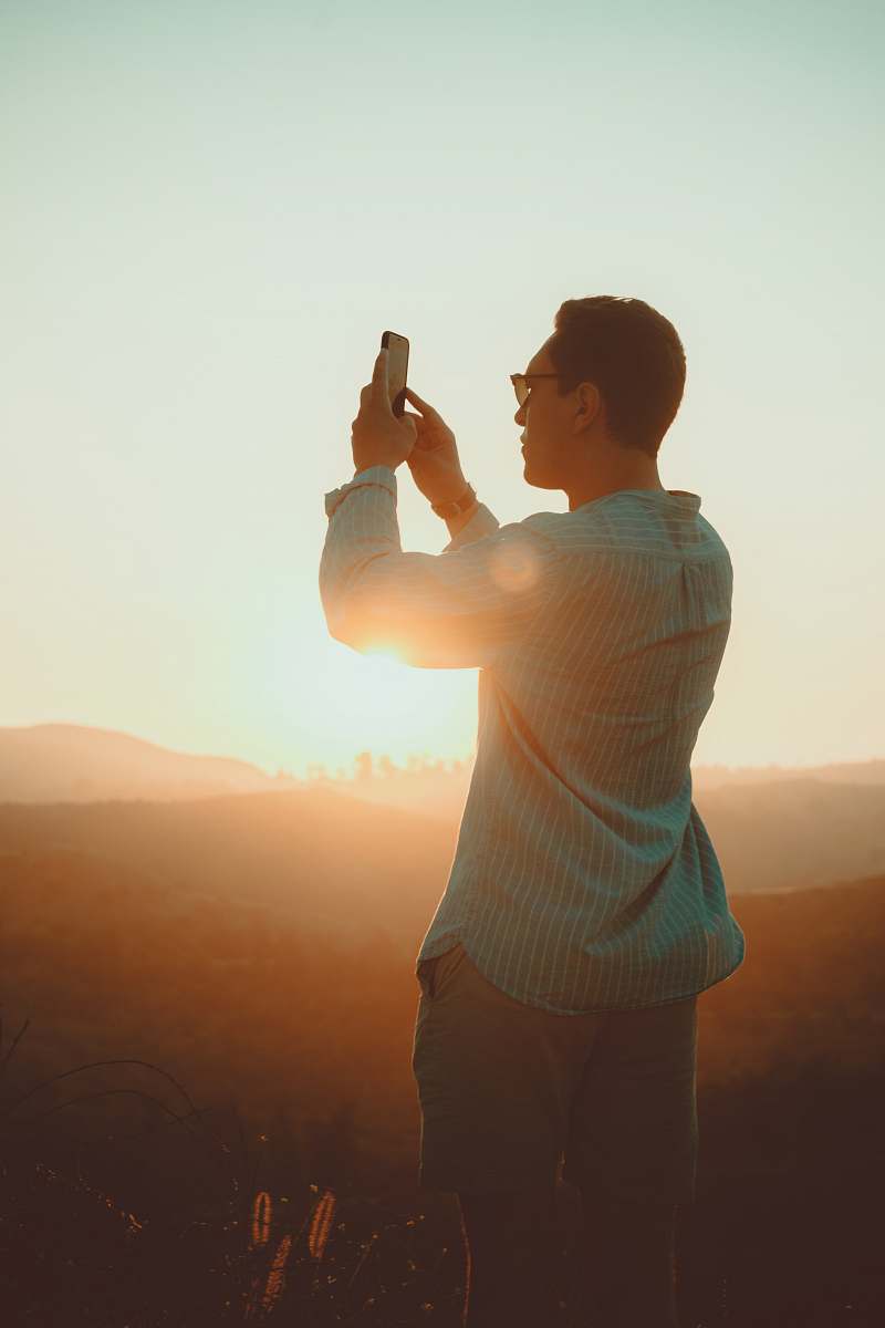 human man wearing green dress shirt taking picture during sunset person