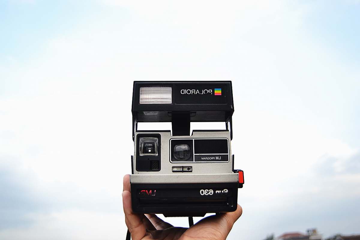 camera person holding black and gray Polaroid 630 instant camera polaroid