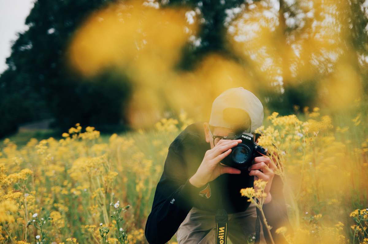 In this stunning image, a human man is seen skillfully utilizing his Nikon DSLR camera to capture the enchanting beauty of a vast field filled with colorful flowers. The scene encapsulates the essence of nature photography, showcasing the vibrant colors and intricate details of the blooms. This captivating shot is perfect for travel articles, nature blogs, or any project that celebrates the beauty of the outdoors and the art of photography.