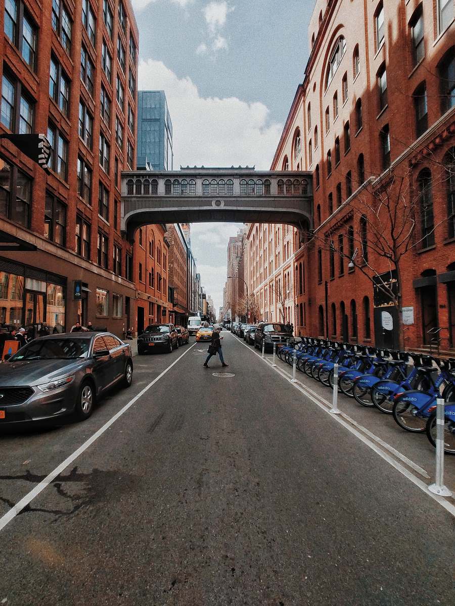 building person crossing asphalt road between buildings chelsea market