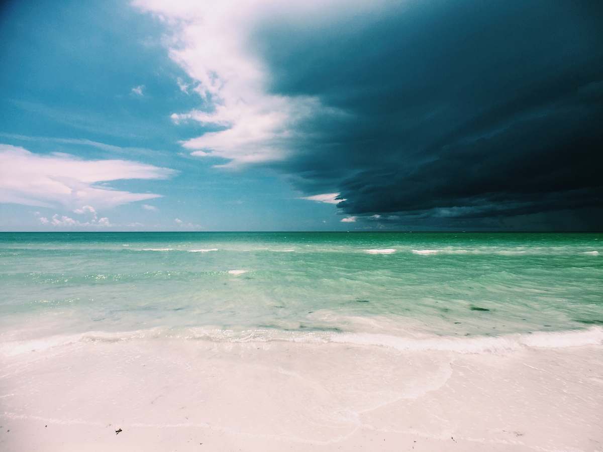 ocean clear white sand beach under cloudy sky coast