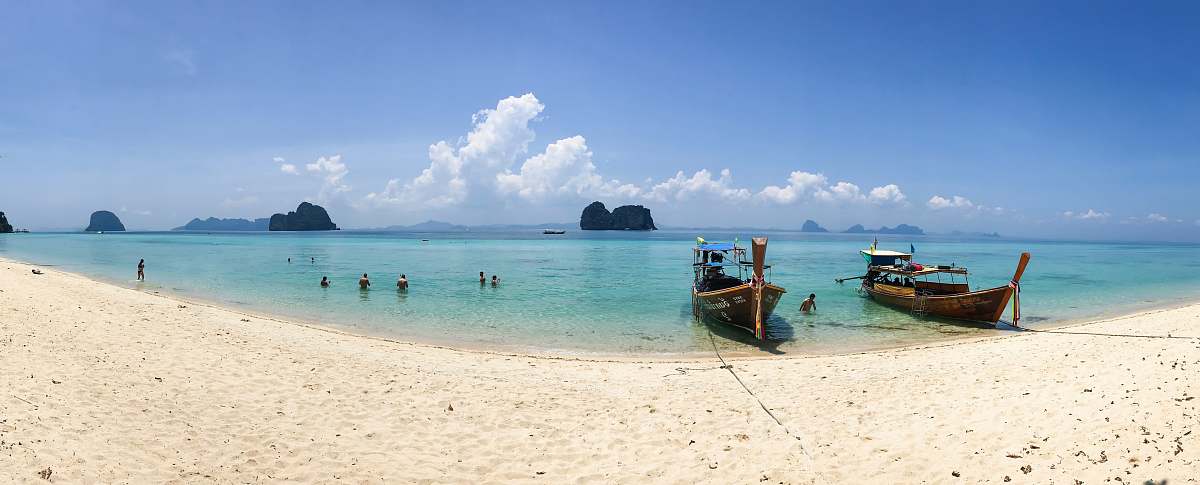 water people on beach beside two brown boats during daytime ocean