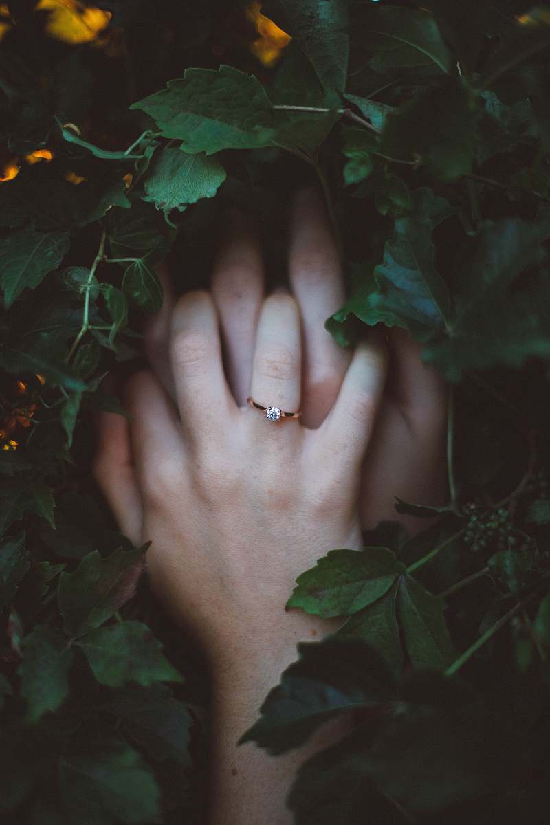 love gold-colored ring on hands surrounded by green leaves wedding