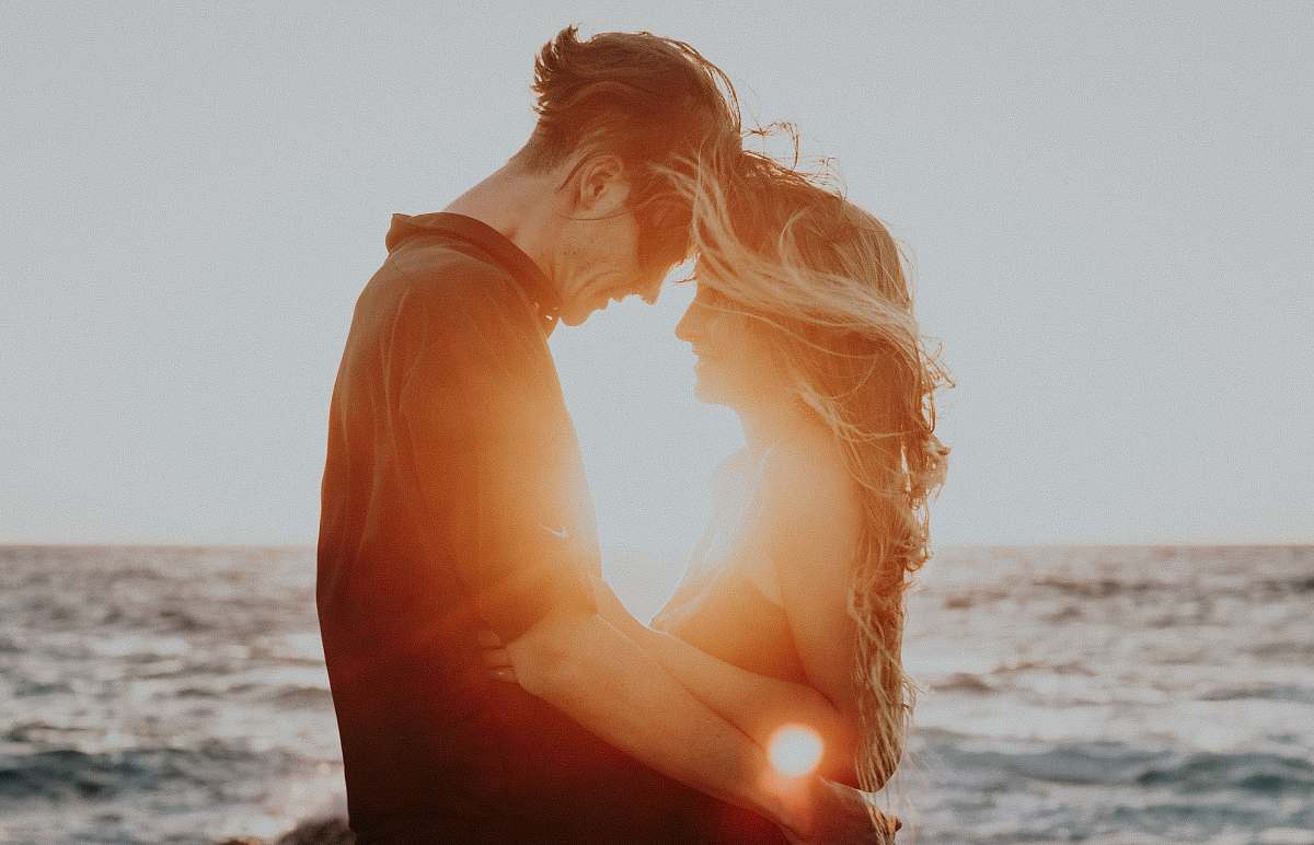 love man and woman hugging near sea during golden hour relationship