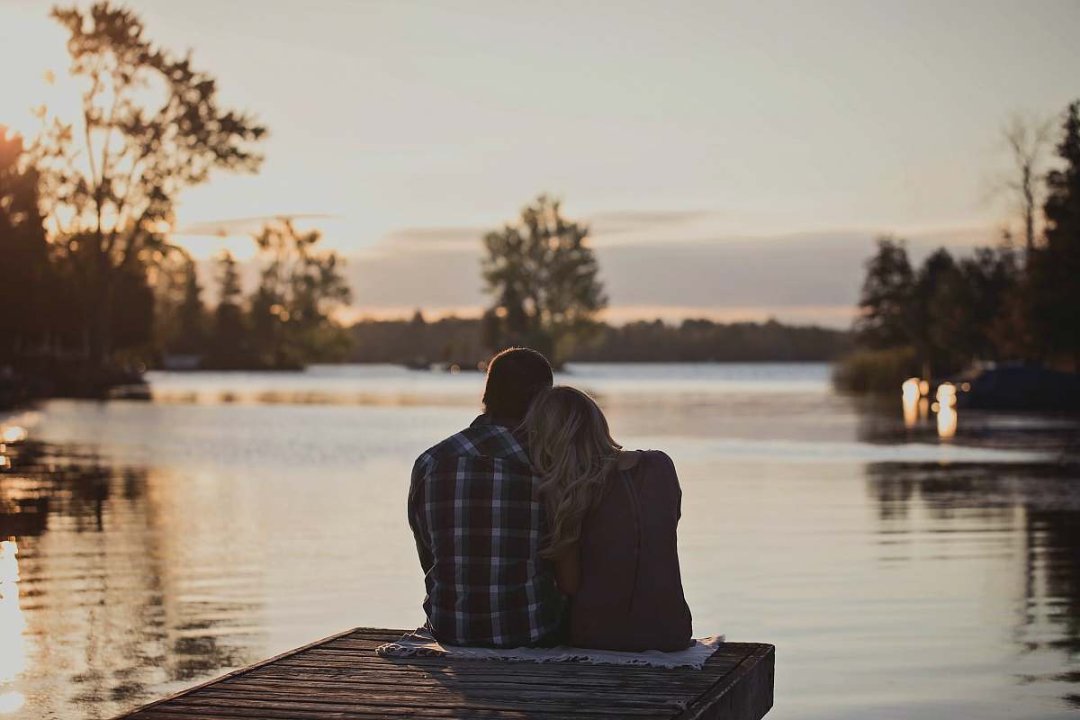 person man and woman sitting on dock during golden hour human