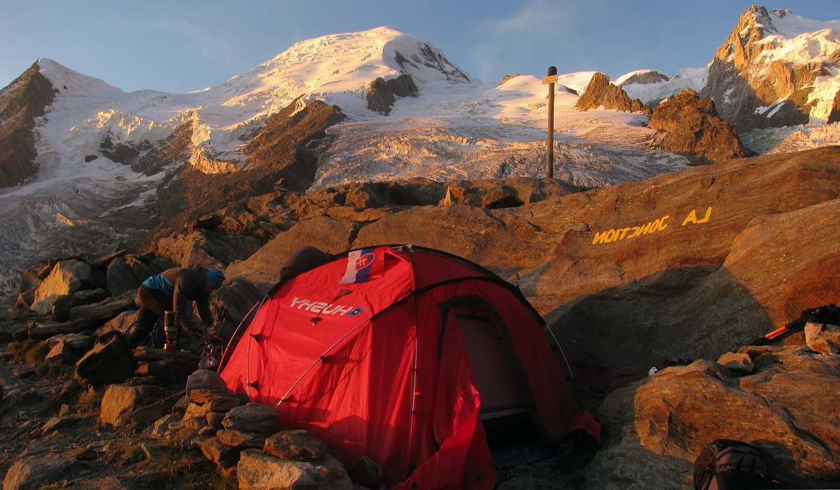 human red and black dome tent on mountain peak person