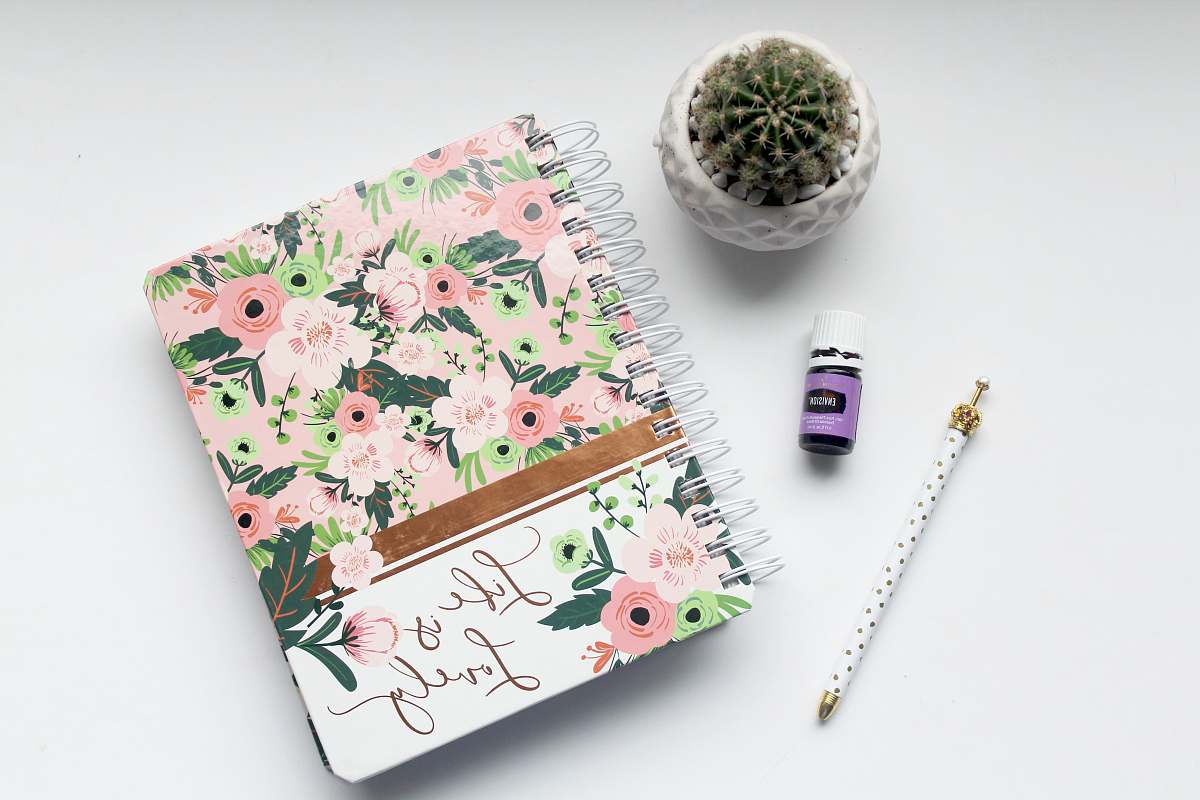 book white and pink floral notebook on table pen