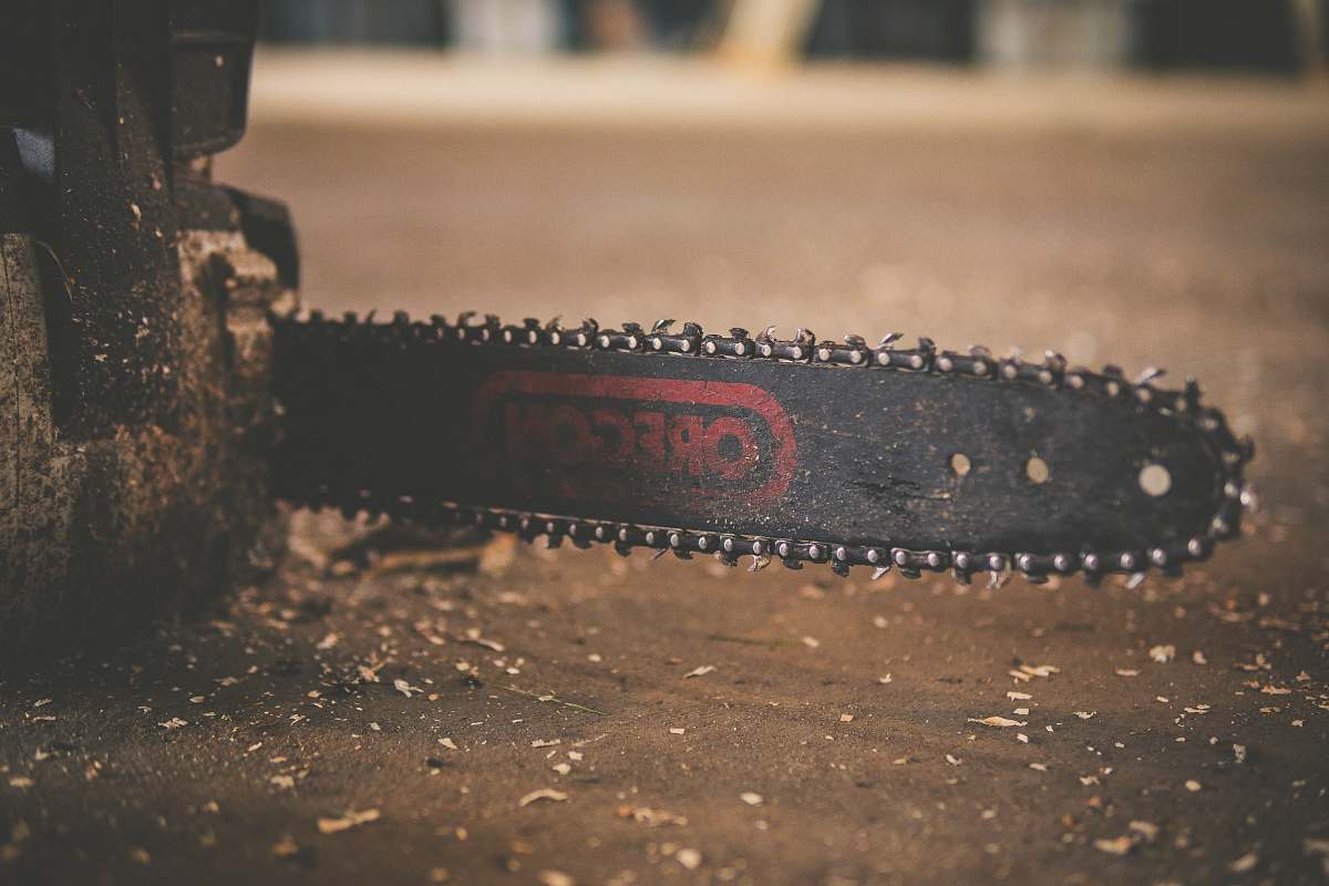 chainsaw black and red Oregon chainsaw on brown wood plank blade