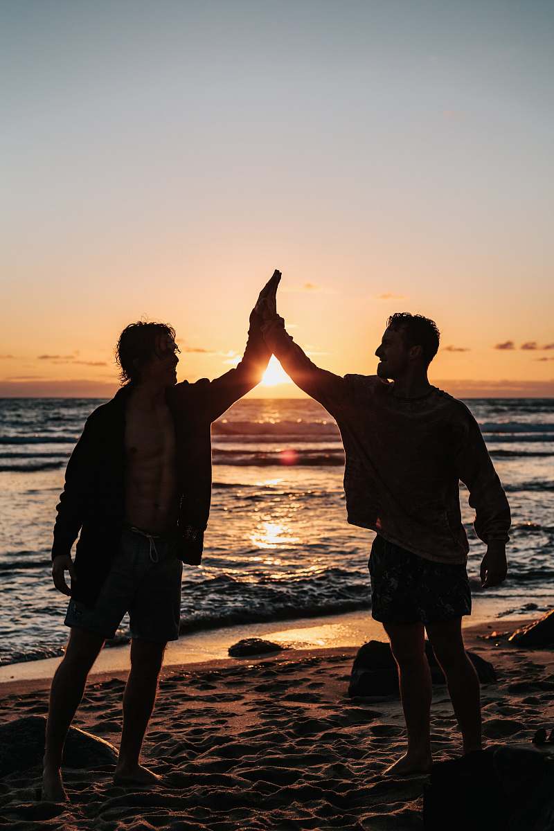 ocean two men clapping each other on shore nature