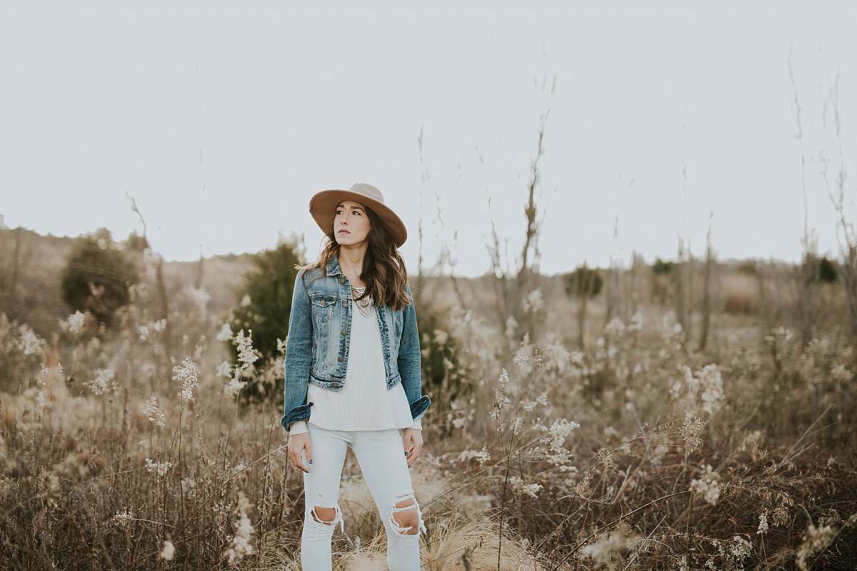 person woman in blue denim jacket surrounded by grass during daytime human