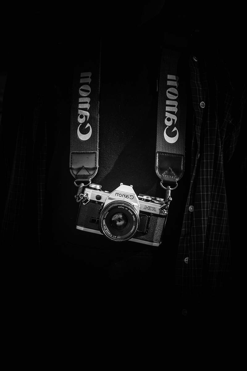black-and-white gray and black Canon camera body with lanyard camera strap
