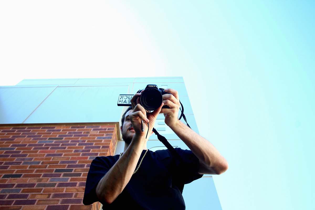 person man standing and using DSLR camera human