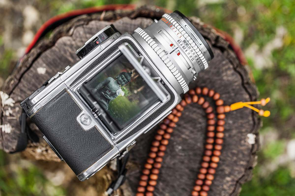 nature selective focus of gray DSLR camera captured Buddha statue digital watch