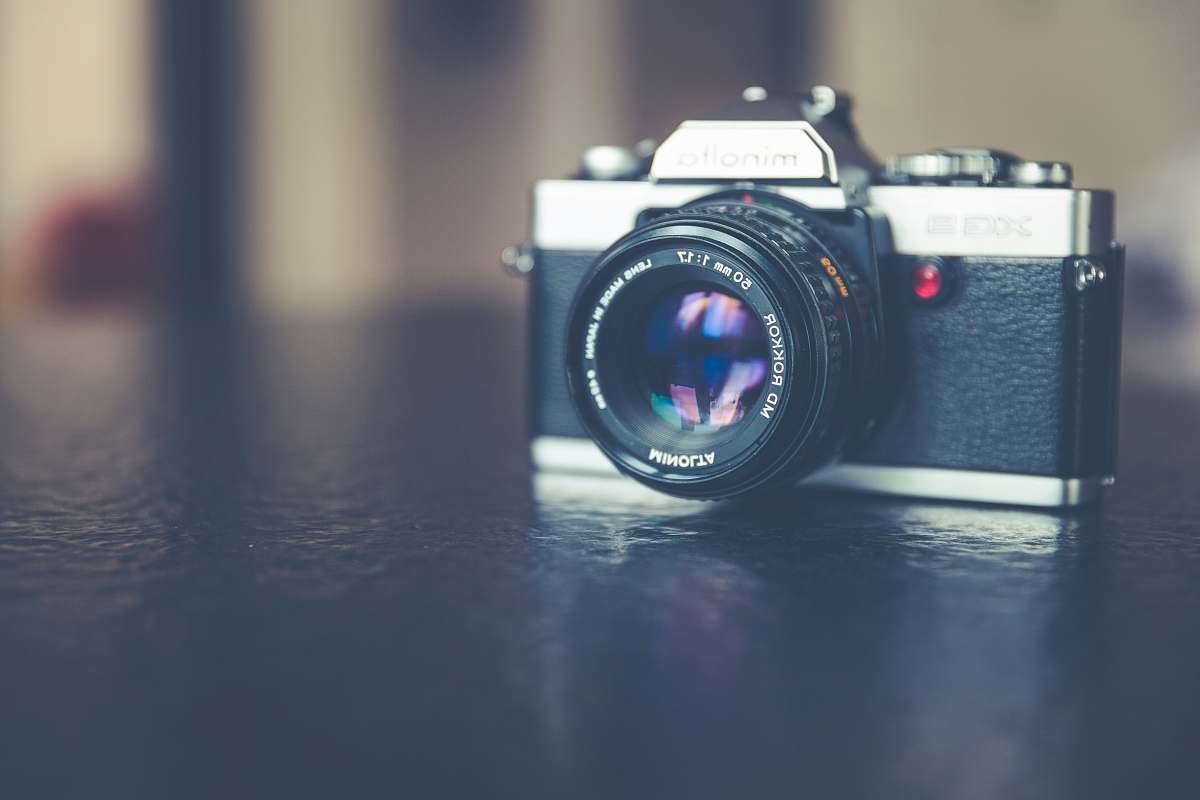 camera silver and black camera on top of black wooden surface lens