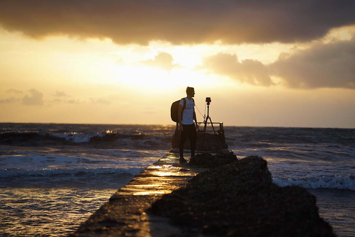 person man carrying backpack standing on dock photo