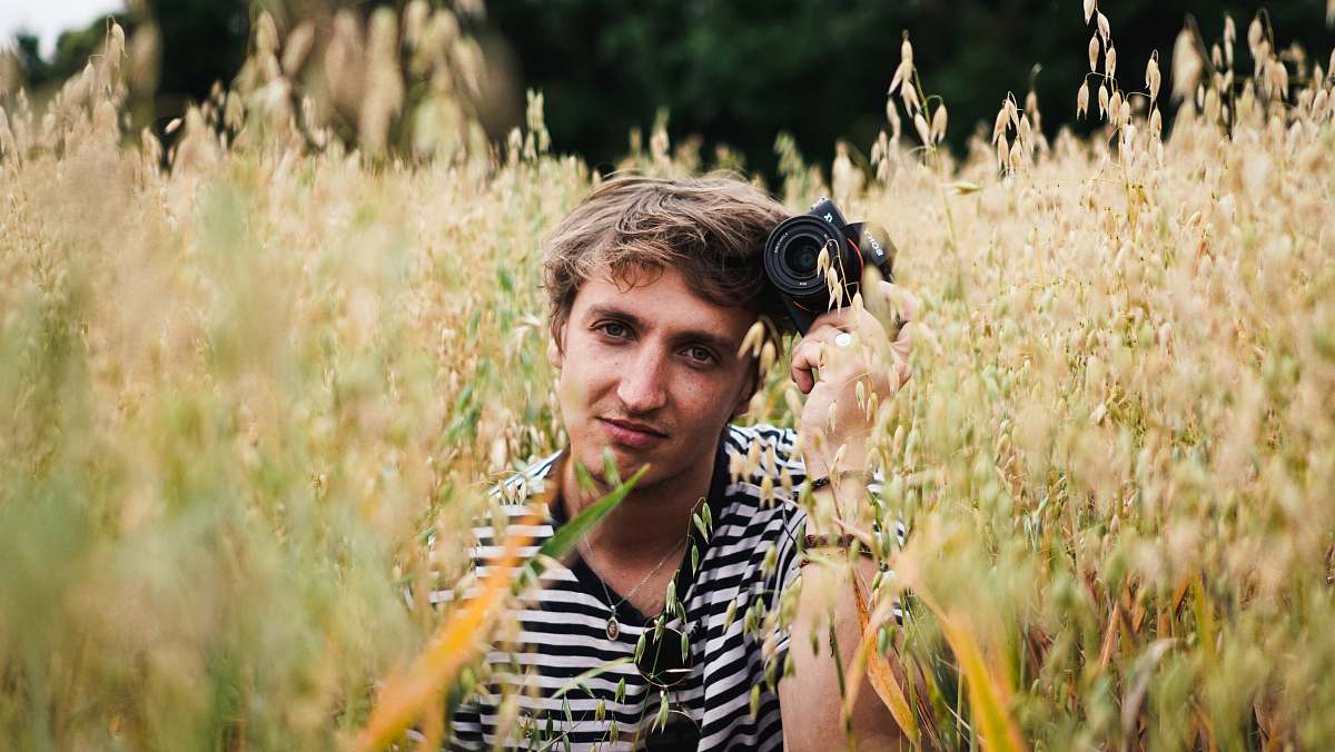 person man holding black camera in field during daytime photo