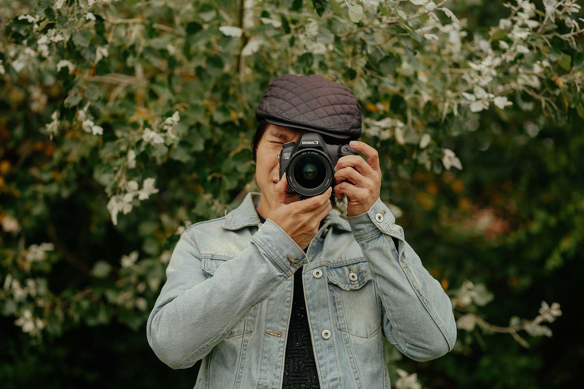 person man holding DSLR camera near plants camera