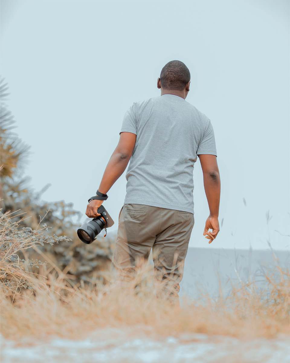 person man holding DSLR camera while walking photo