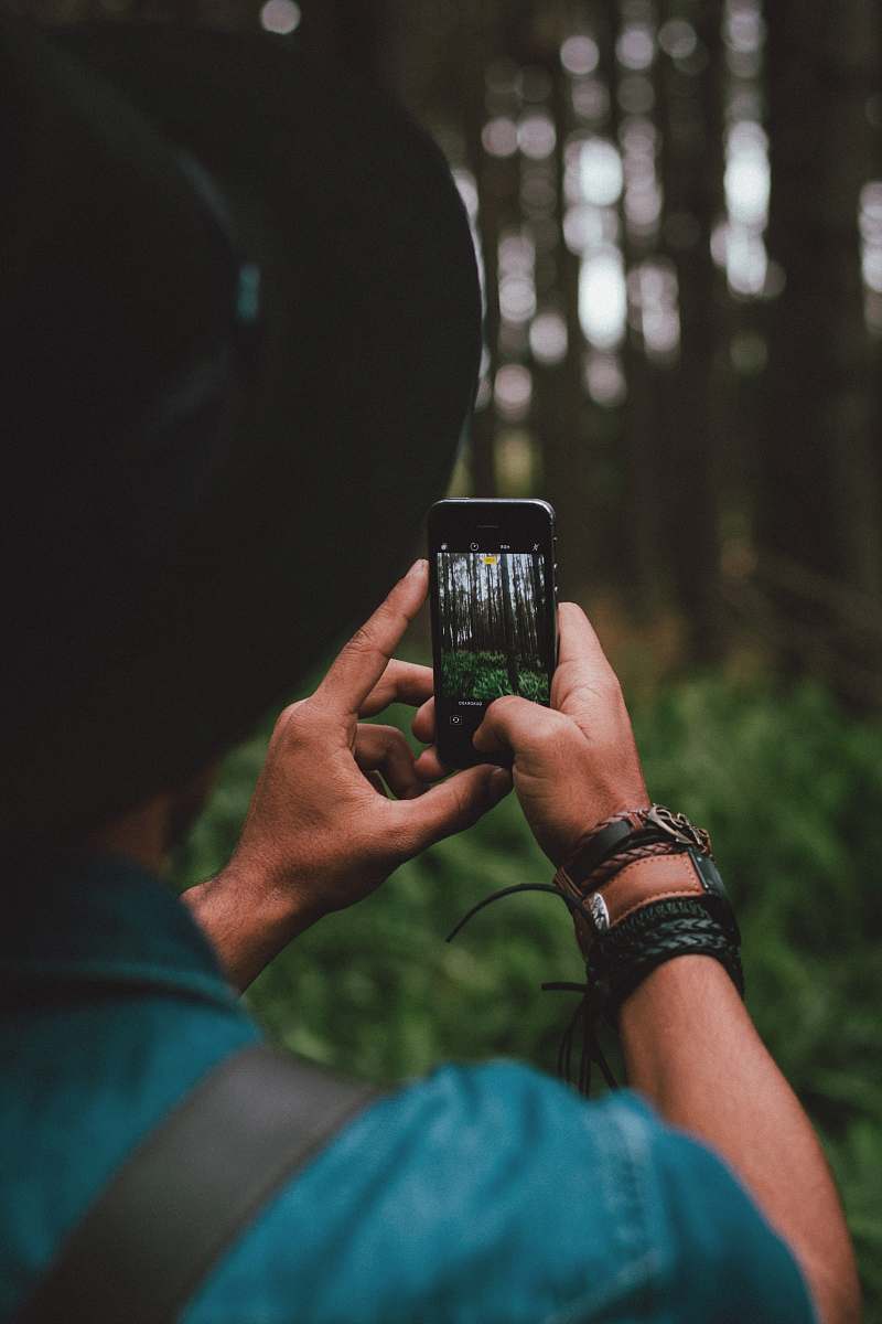 person man holding iPhone 5s forest