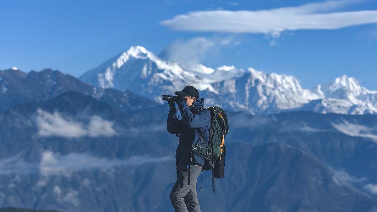 person man standing on top of mountain holding binoculars photo