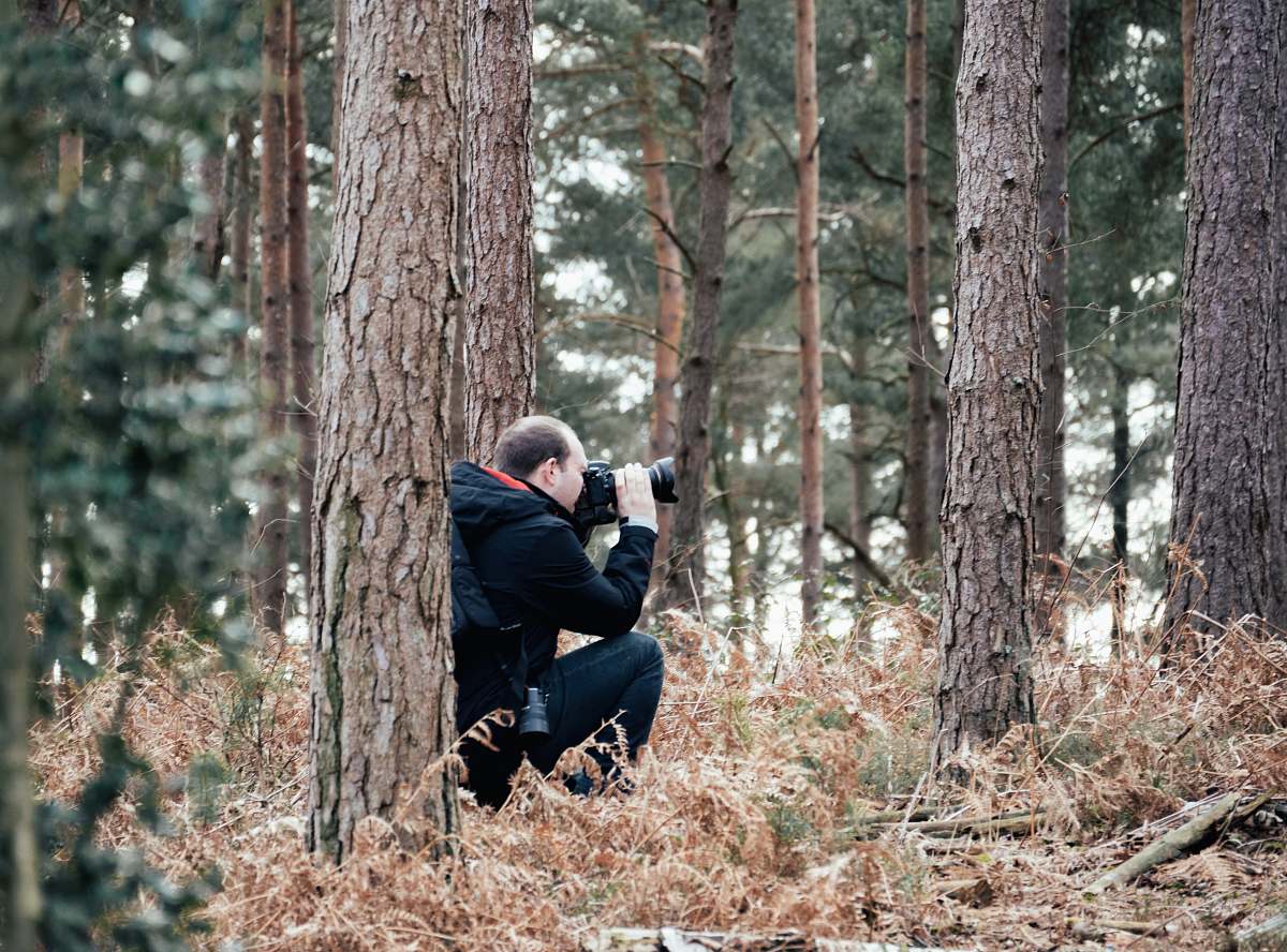 person man taking picture in the woods using a DSLR camera photographer