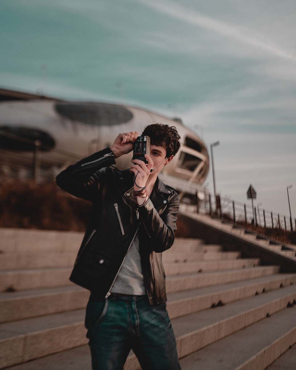 person man wearing black leather jacket standing and using camera photographer