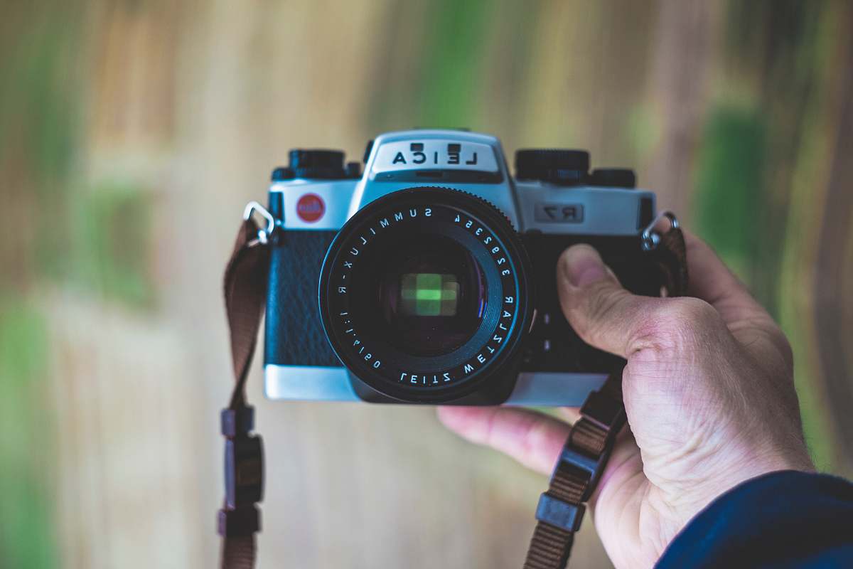 person person holding gray Leica SLR camera electronics