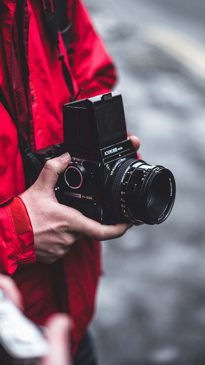 camera selective focus photography of person holding black DSLR camera electronics