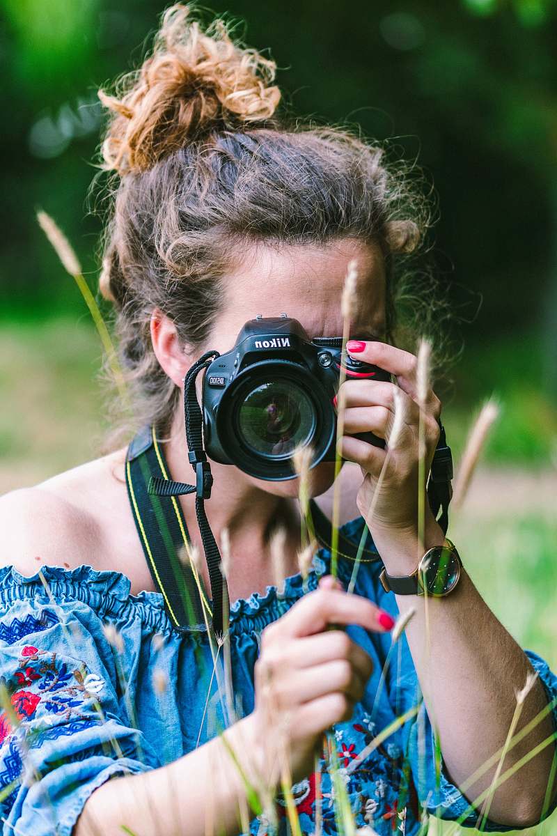 person woman wearing blue dress holding camera during daytime camera