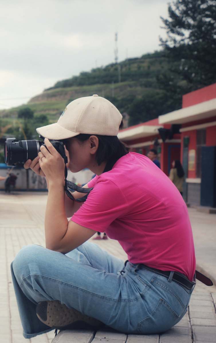 person women holding a camera while sitting during daytime apparel