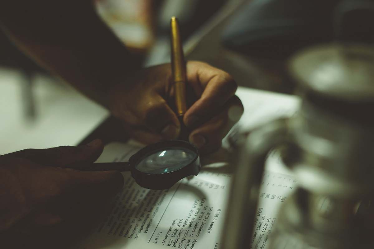 book person holding magnifying glass writing