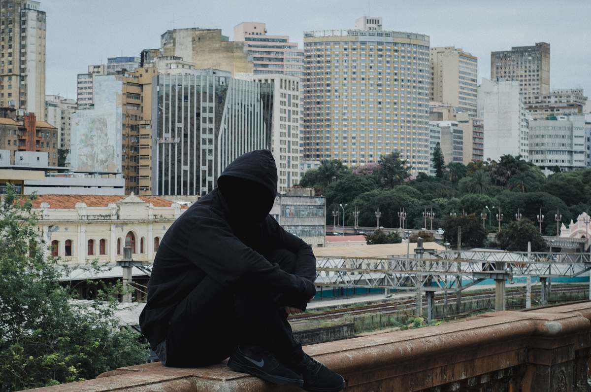 person man wearing hooded jacket sitting on beige concrete human