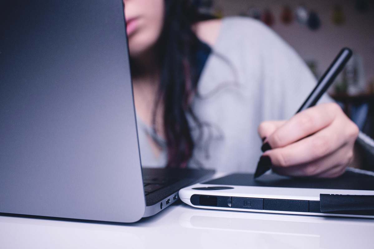 person woman using drawing pad while sitting in front of laptop human
