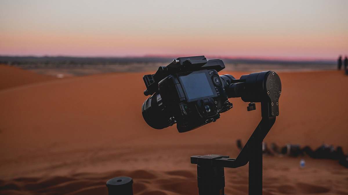 human black DSLR camera mounted on stabilizer at the desert soil
