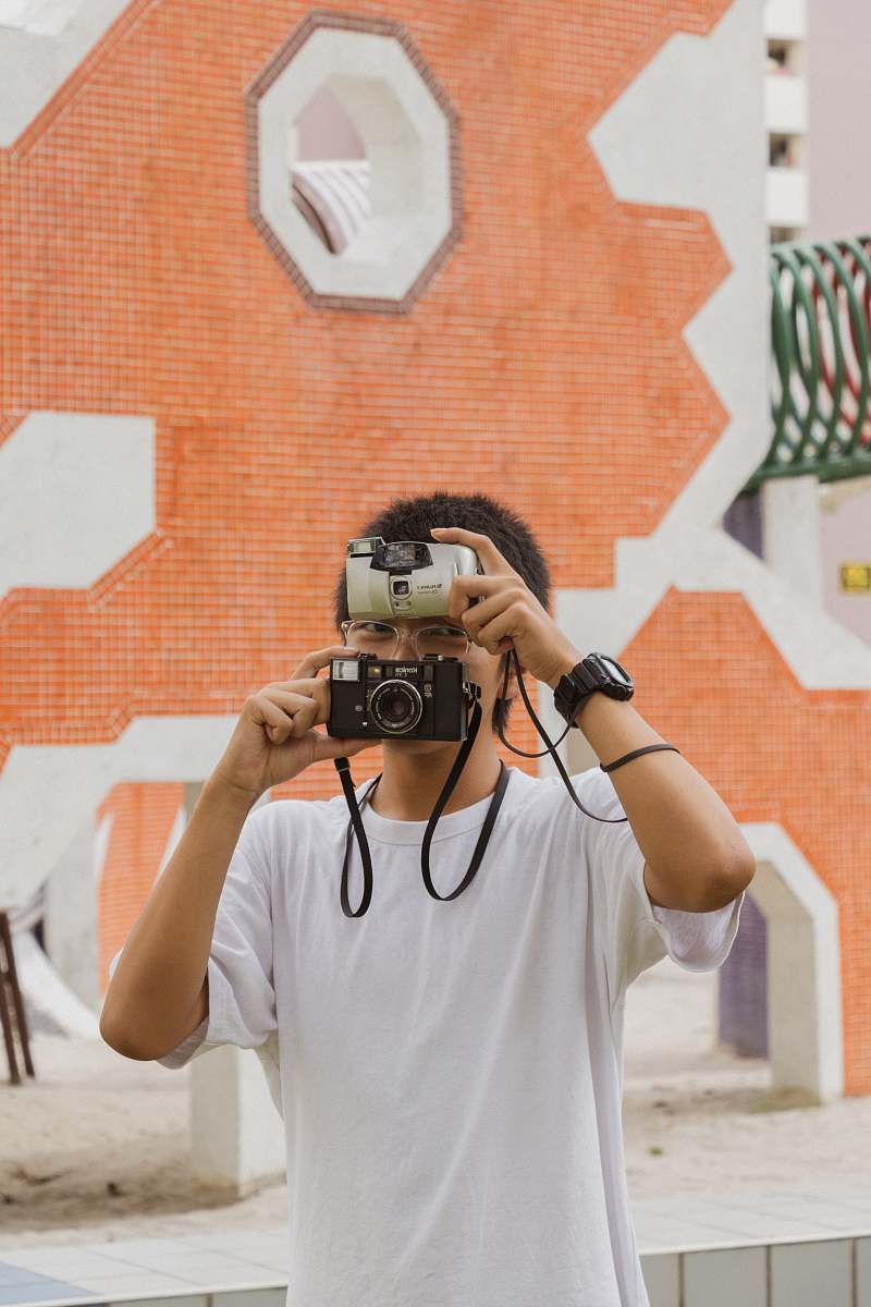 human man covering his face with two cameras camera