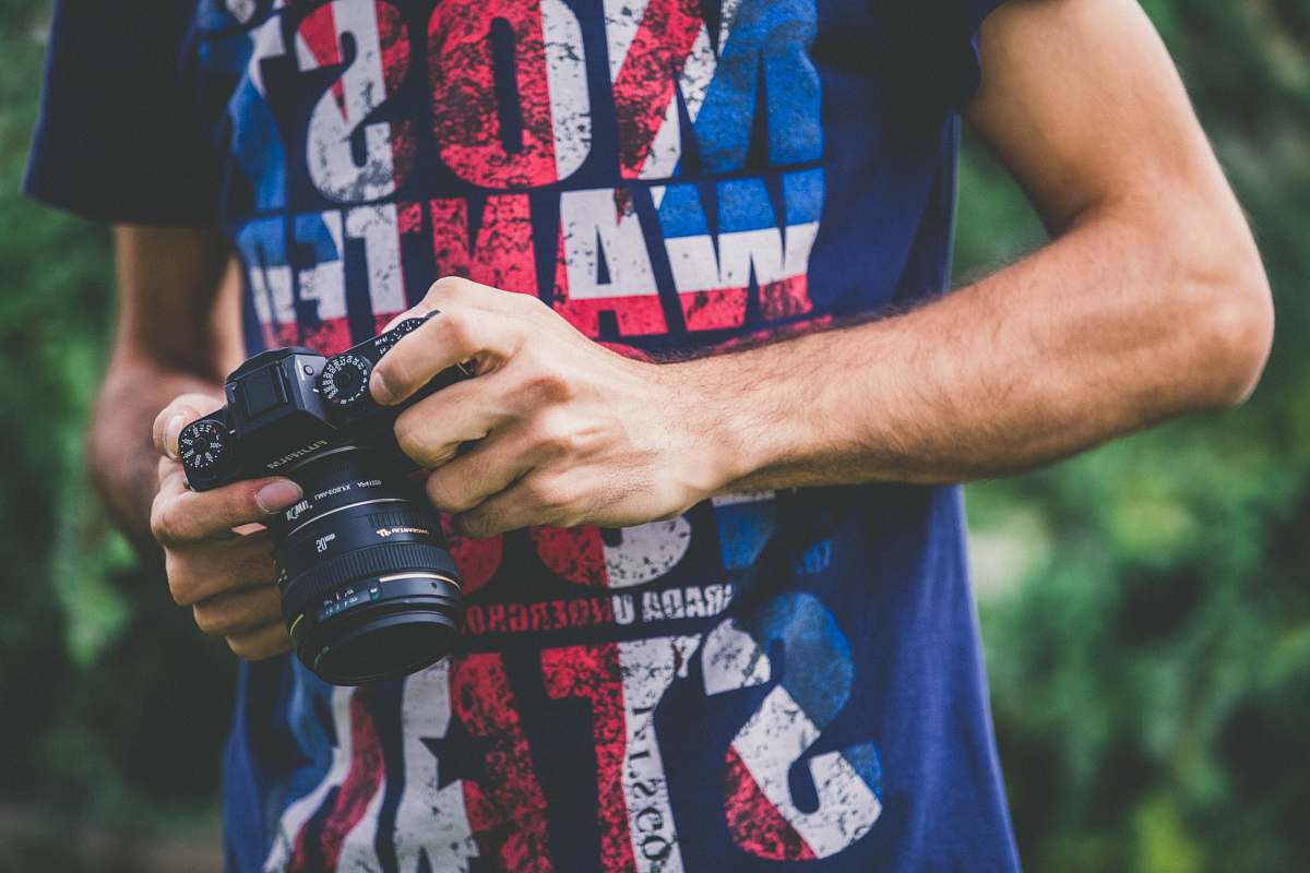 people man in blue shirt holding DSLR camera camera